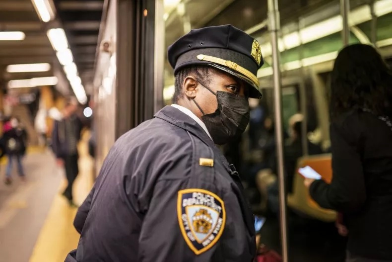 A police officer leaning their head into a subway car