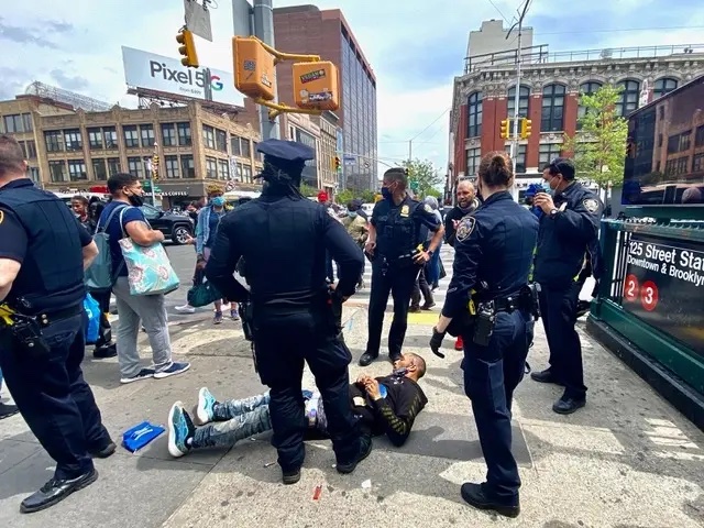 Police officers gathered around a man on the ground